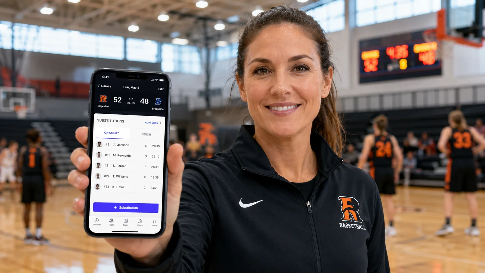 A coach holding a phone showing Run The Bench's recommended substitution during a game.